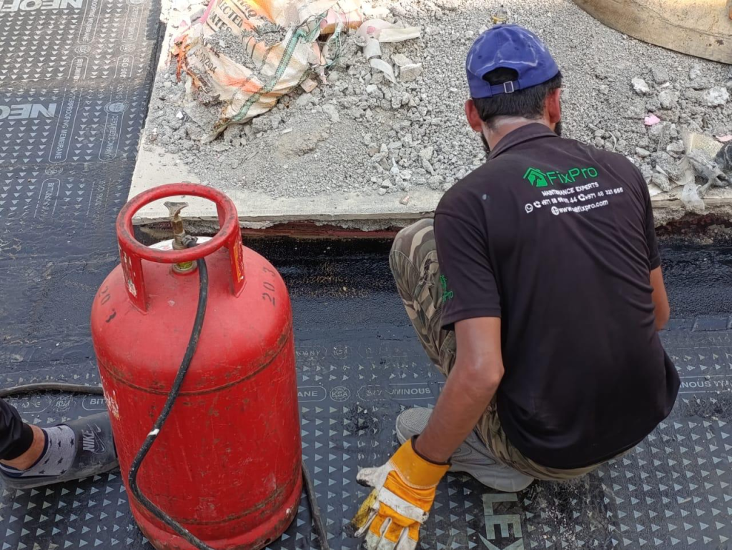 FixPro technician applying a bituminous waterproofing membrane to a roof slab with a gas torch, Dubai